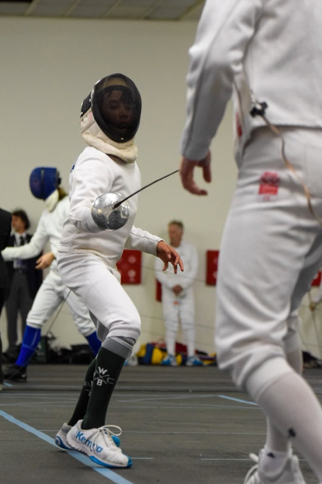 Marin Fencing Academy — A masked fencer mid-riposte, blade bending against an opponent