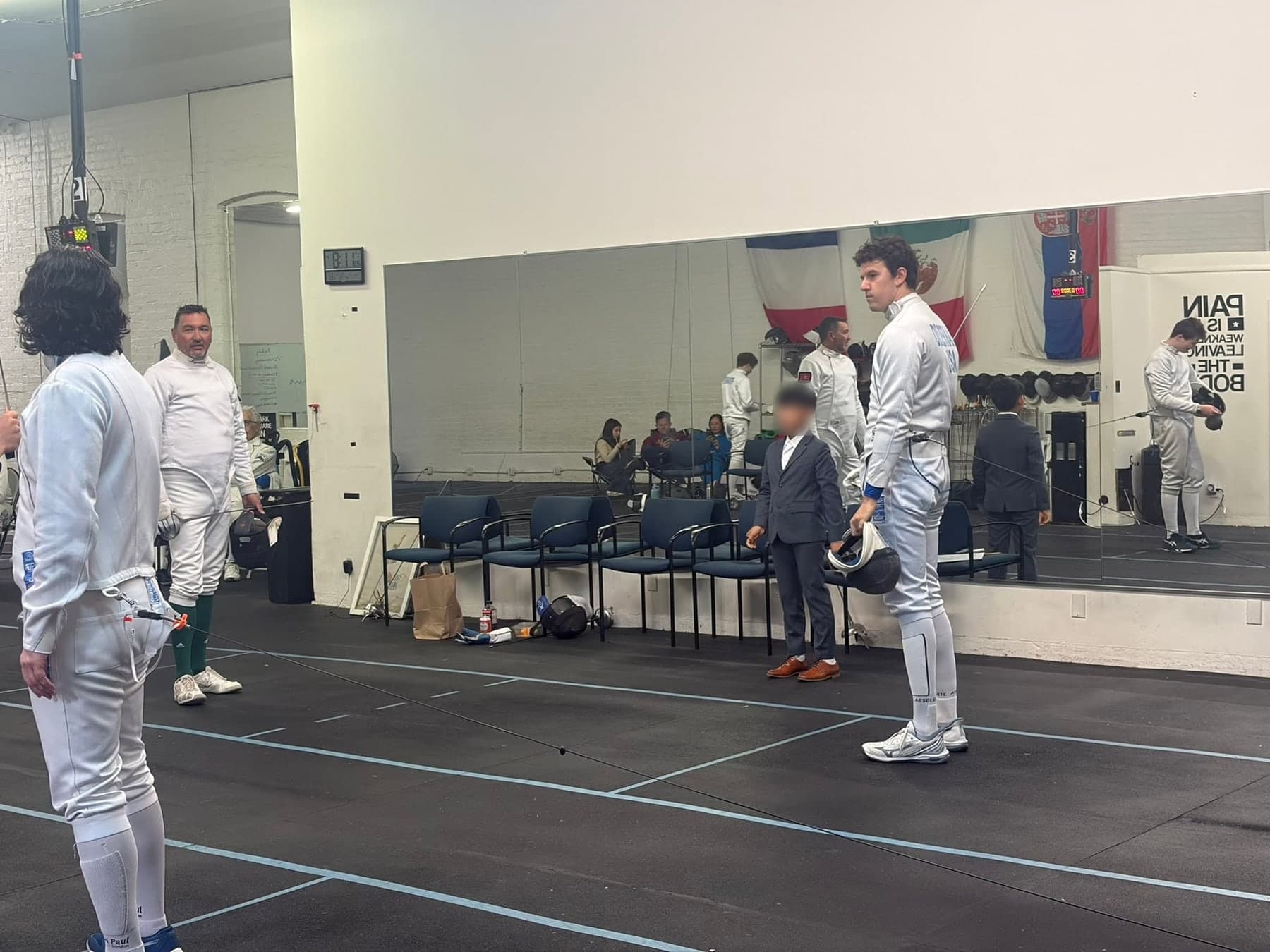A refereed bout at Marin Fencing Academy, fencers waiting along the strip