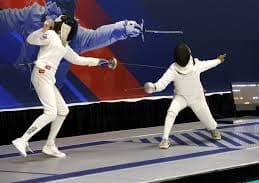 Two fencers mid-bout on a raised finals piste at a national event