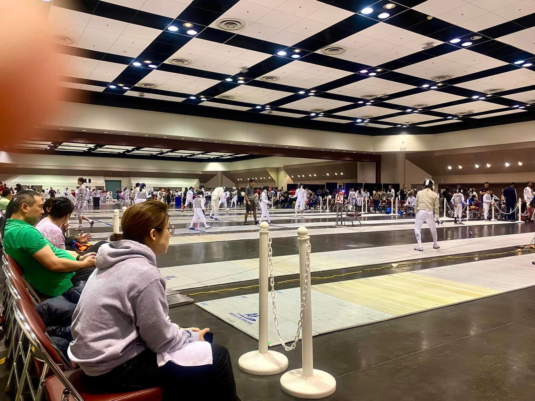 A sanctioned tournament in a large hall, with bouts running on many strips at once