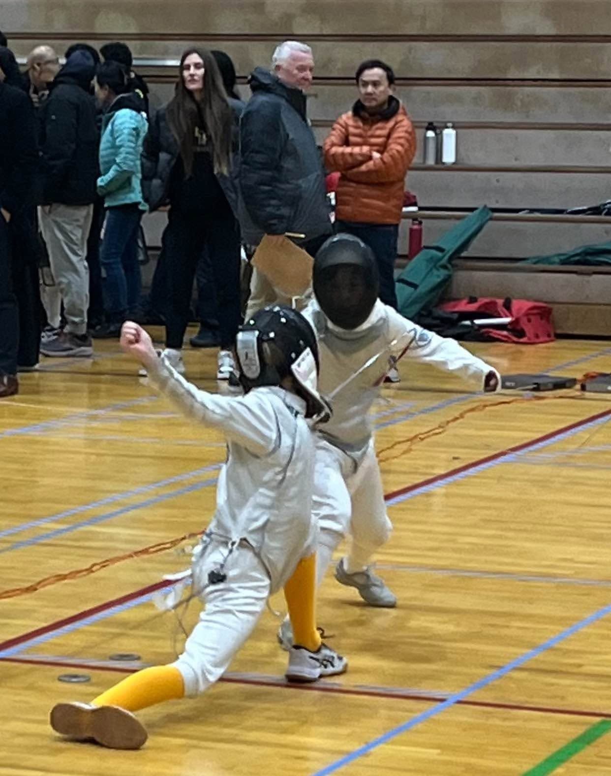 A young fencer lunging during a bout